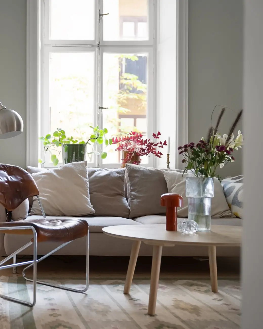 Dezelfde voorkamer na de renovatie, met zetel, bijzettafel en planken vloer