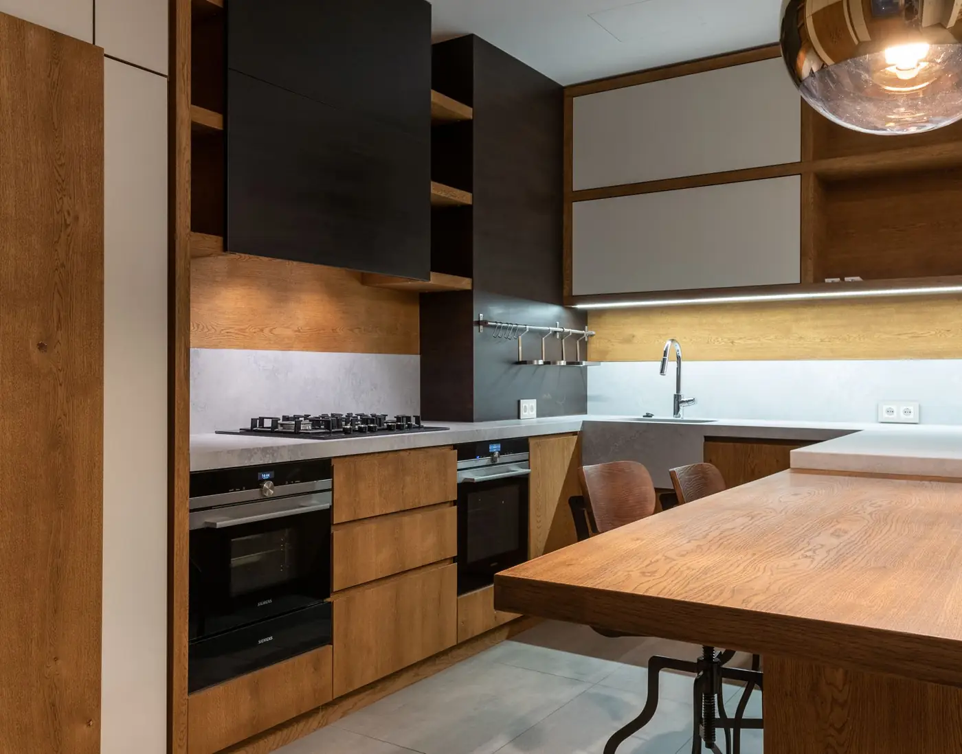 Keuken in eik met zwarte kasten, inbouwovens en een houten eiland