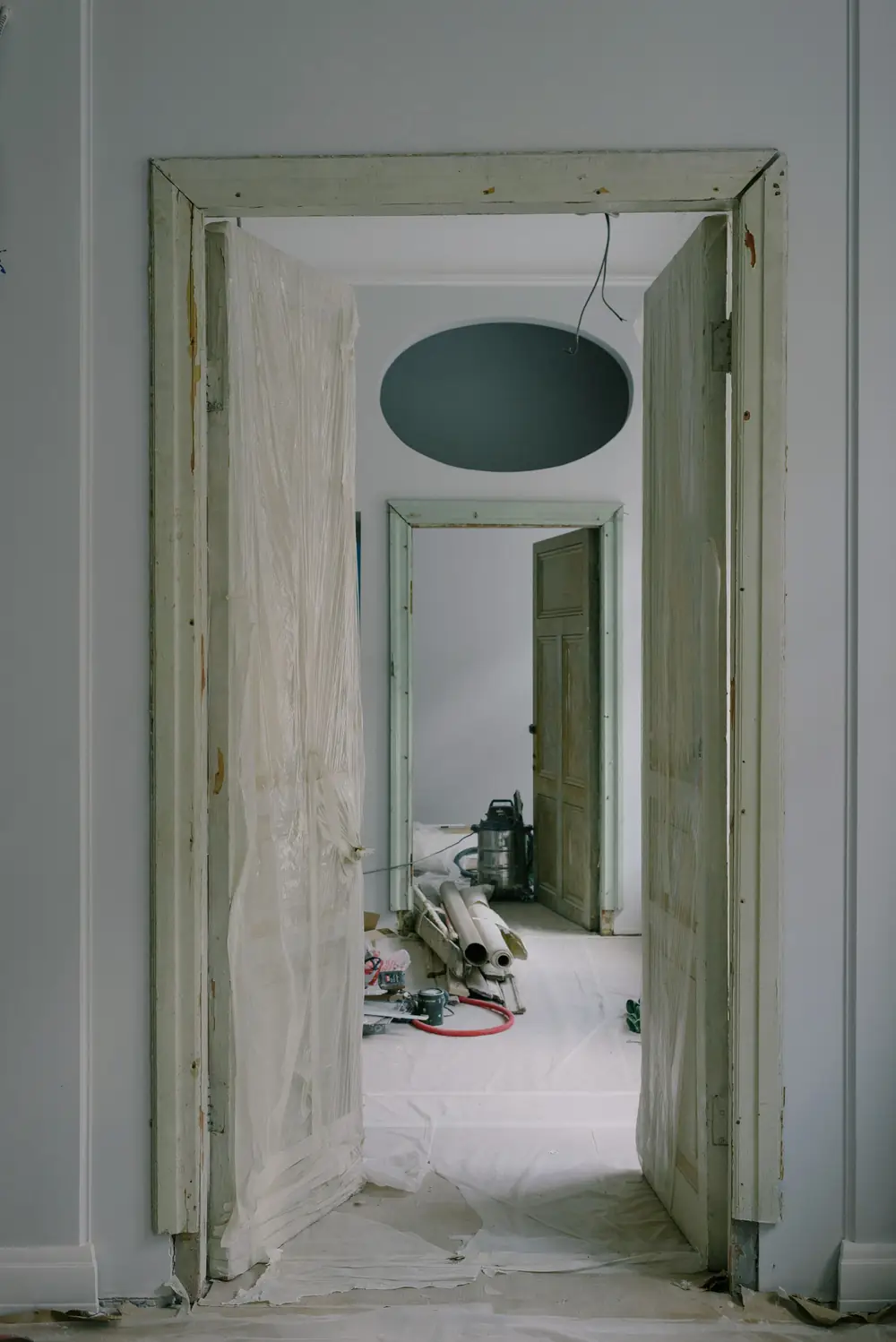 Doorkijk door een woning in renovatie, de deuren ingepakt in folie