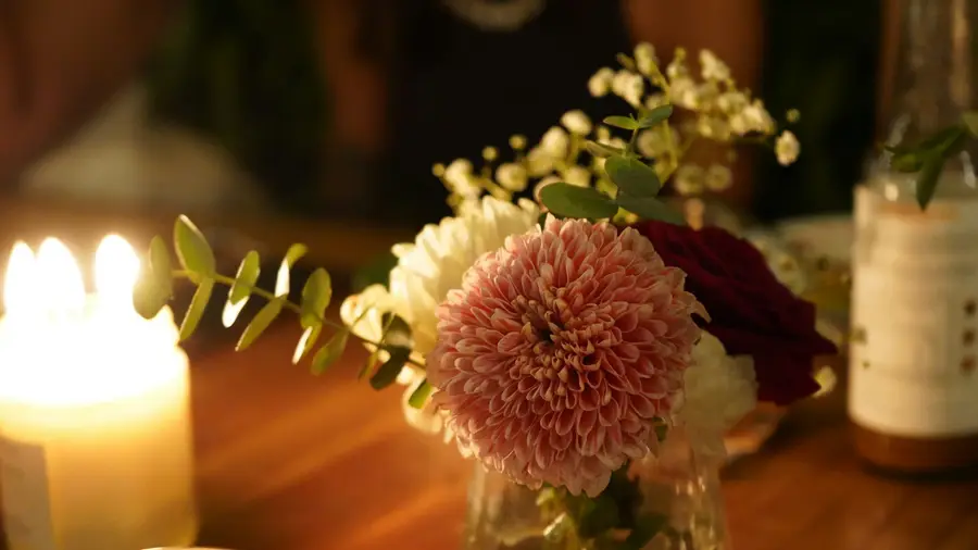 Een kaars en een dahlia op een houten tafel