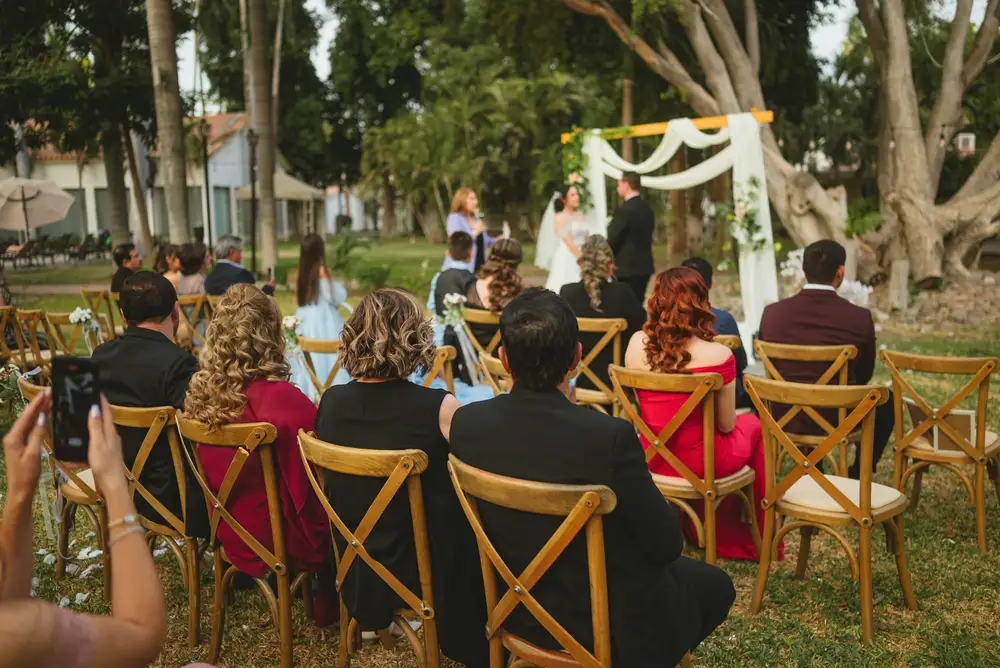 Gasten op houten stoelen in de tuin tijdens een ceremonie