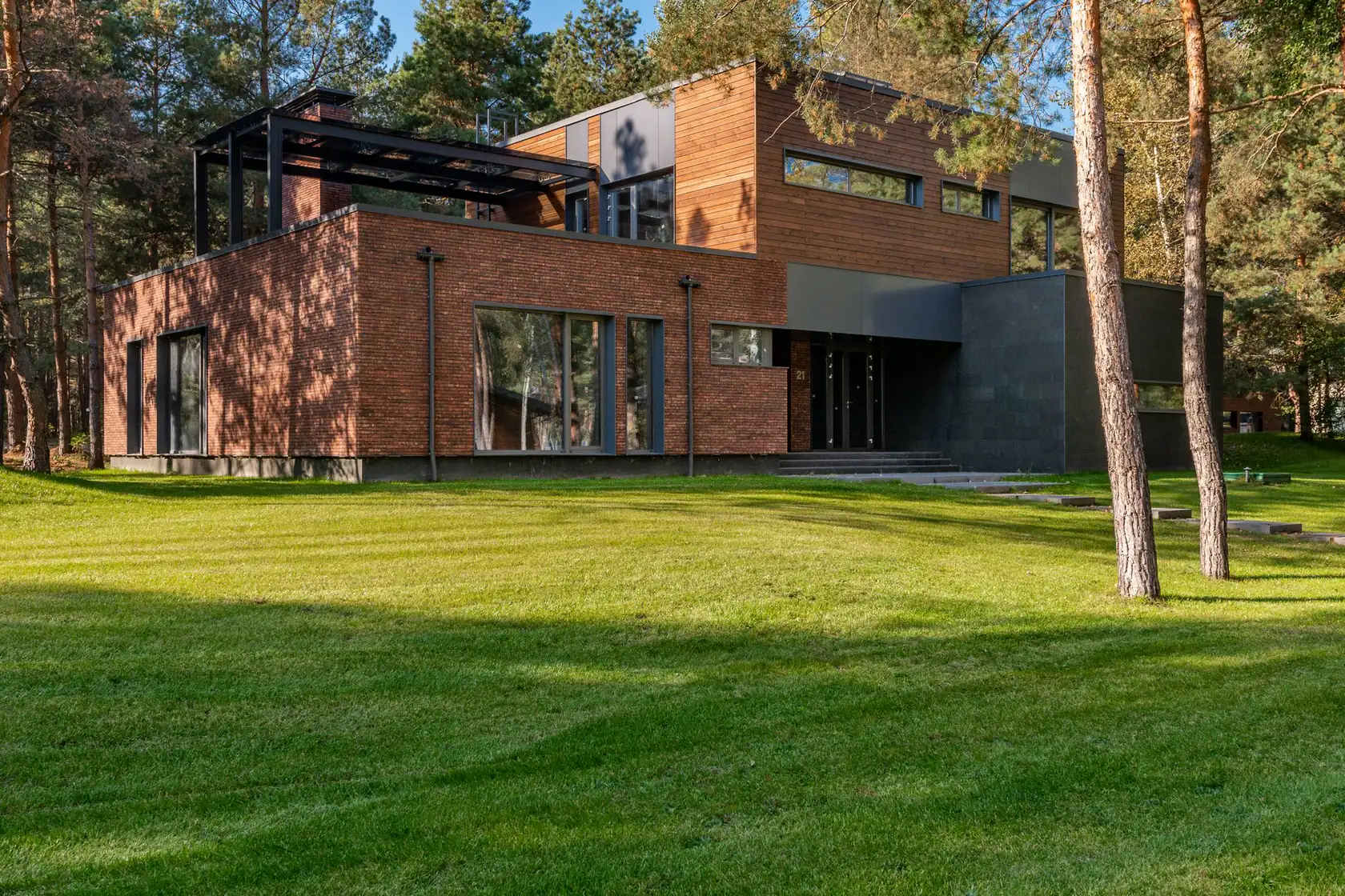 Villa in baksteen en hout tussen de dennen, met een groot gazon