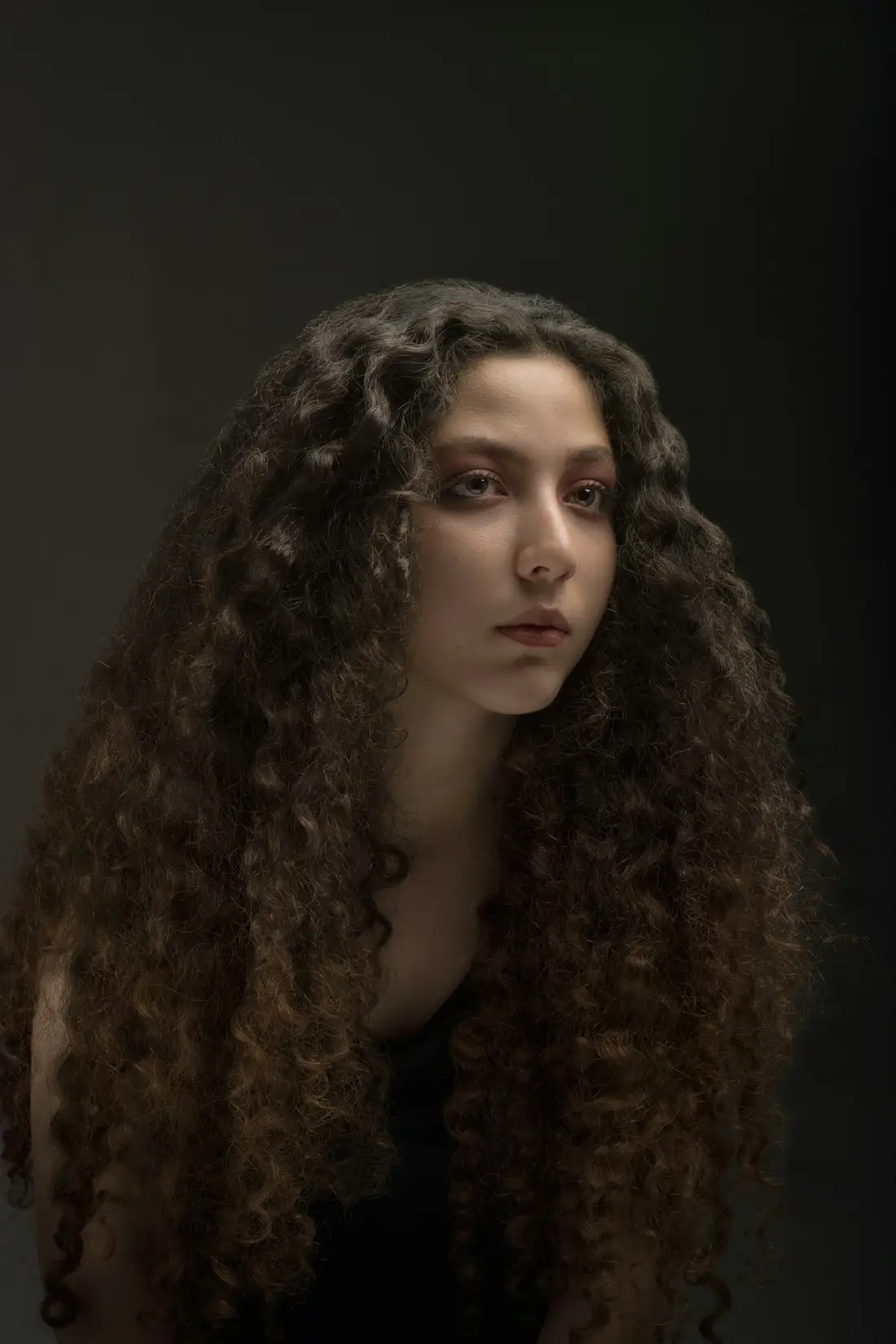Een vrouw met lange donkere krullen in zacht licht